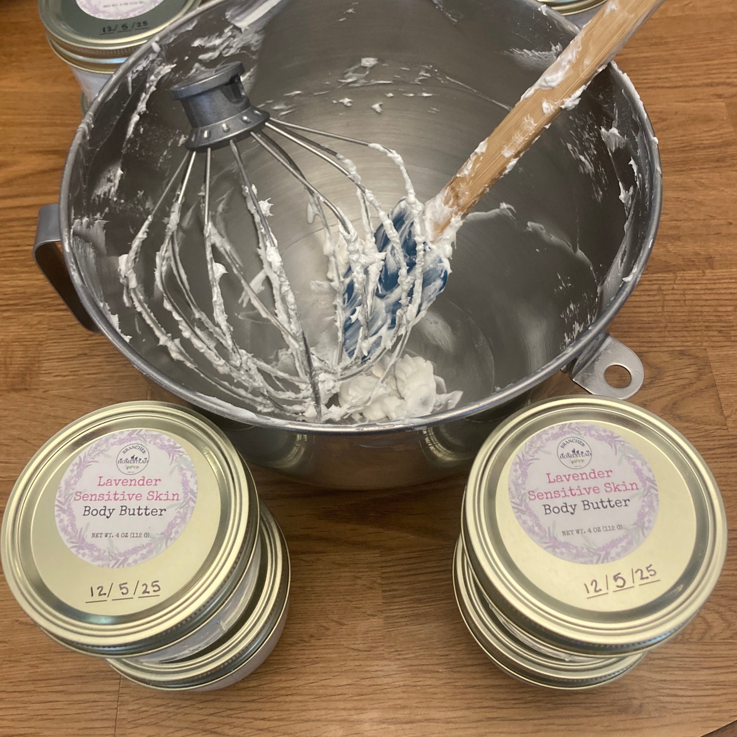 Bowl with a whisk and containers of lavender body butter on a wooden surface