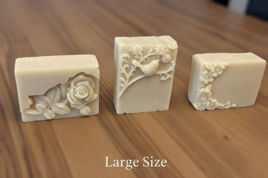 Three large soap bars with floral designs on a wooden surface