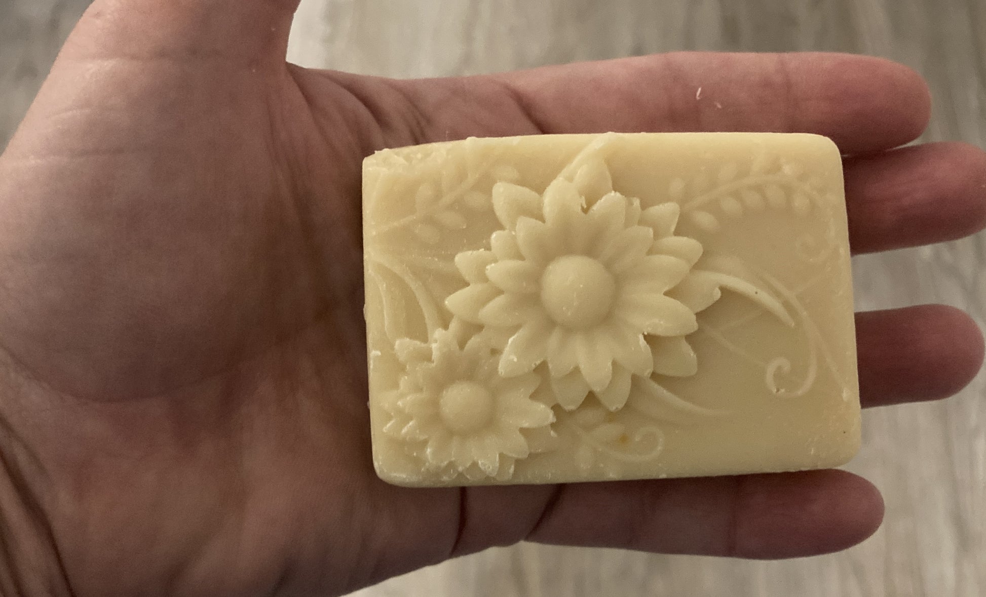 Bar of soap with a floral design held in a hand